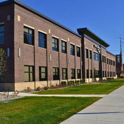 Exterior of Great Lakes Bay Health Centers Old Town in Saginaw, Michigan, featuring masonry work by Boettcher Masonry with basketweave and running bond brick patterns, blue sign, and clear blue skies.