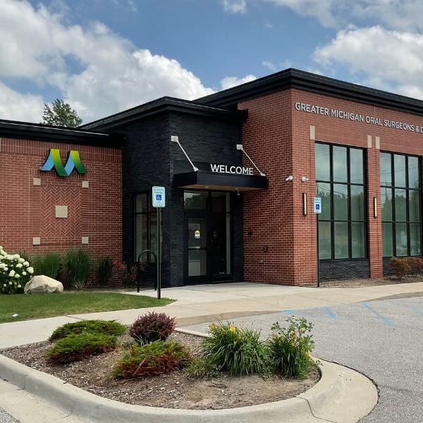 Exterior of Greater Michigan Oral Surgeons & Dental Implant Center in Midland, MI, featuring expert masonry by Boettcher Masonry with running bond, stack bond, and herringbone brick patterns under blue skies.