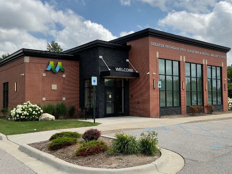Exterior of Greater Michigan Oral Surgeons & Dental Implant Center in Midland, MI, featuring expert masonry by Boettcher Masonry with running bond, stack bond, and herringbone brick patterns under blue skies.