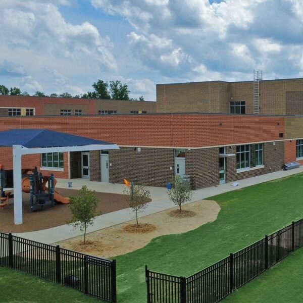 Exterior of E-53 Pleasant Plains Elementary School featuring 320,000 utility bricks, special shapes by Palmetto, and 7,500 colorful glazed bricks from Belden Brick. Playground and fence.