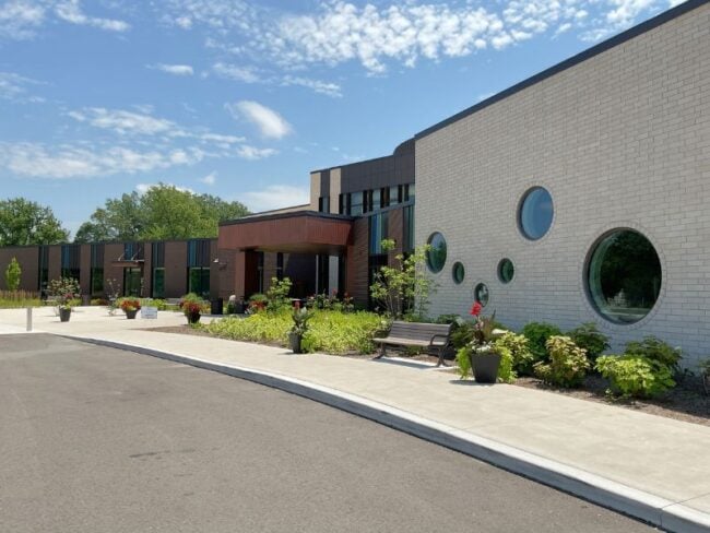 Walkway leading up to Greater Midland Community Center with Boettcher Masonry brick veneer, round windows, and landscaped surroundings.