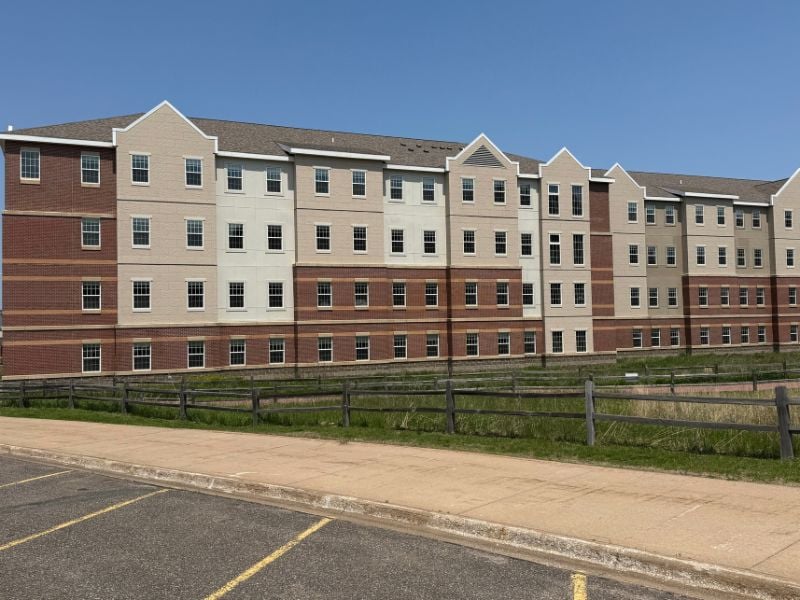 Exterior of Northern Michigan University’s Weston Hall featuring Boettcher Masonry’s multi-textured and multi-colored brickwork, with landscaped green space and parking lot in front.