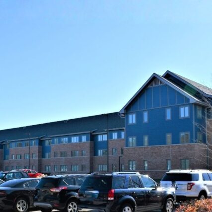 Exterior of Northwood University’s North Village Apartments surrounded by trees, featuring Boettcher Masonry brickwork that blends with the natural wooded setting.