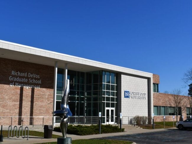 Entrance of Northwood University’s Richard DeVos Graduate School of Management featuring light and dark brick veneer over CMU with Boettcher Masonry’s Arriscraft clip system and statue in front.
