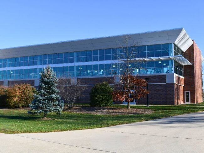 Exterior of Saginaw Valley State University’s Ryder Center Addition with brick, insulated metal wall panels, and glass designed to complement the existing campus architecture.