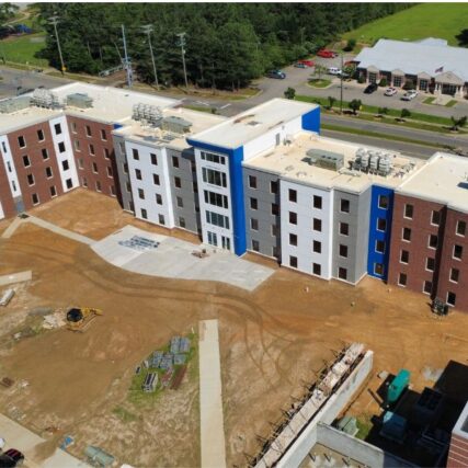 Exterior of Fayetteville State University residence hall under construction, showcasing Boettcher Masonry’s multi-colored brickwork and architectural bump-outs; building structure complete, sidewalks unfinished.